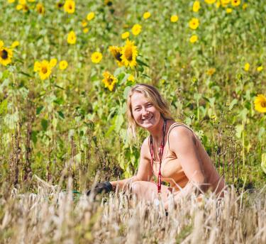 A Eden employee gardening looking to the camera surrounded by sunflowers